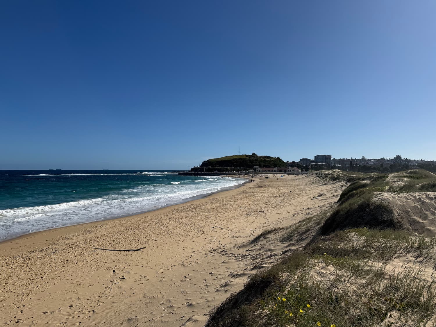 Nobbys Beach in Newcastle mit Sanddünen und Nobbys Head in der Ferne